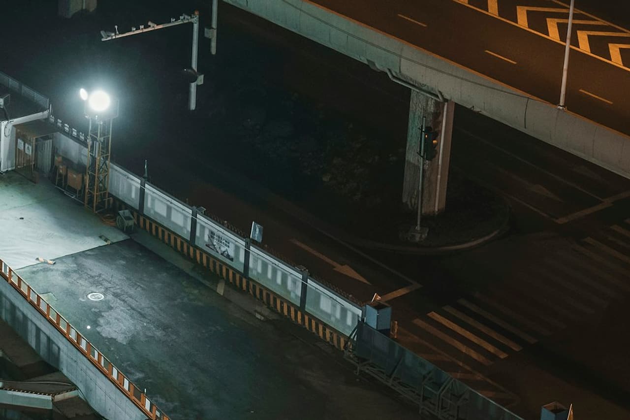 Temporary floodlights illuminate an empty, guarded work area at night.