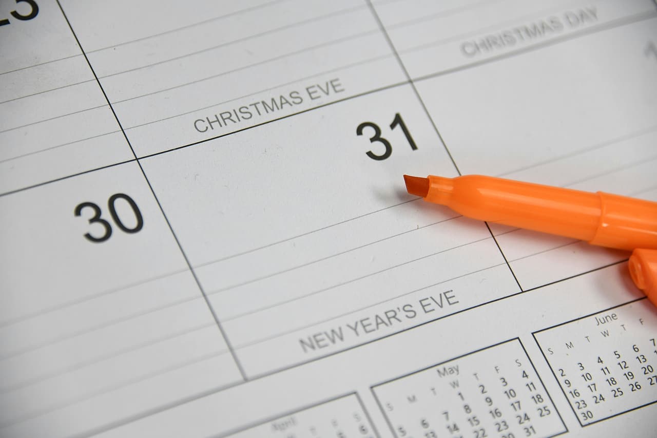 An orange marker rests on a paper calendar beside the dates 30 and 31.