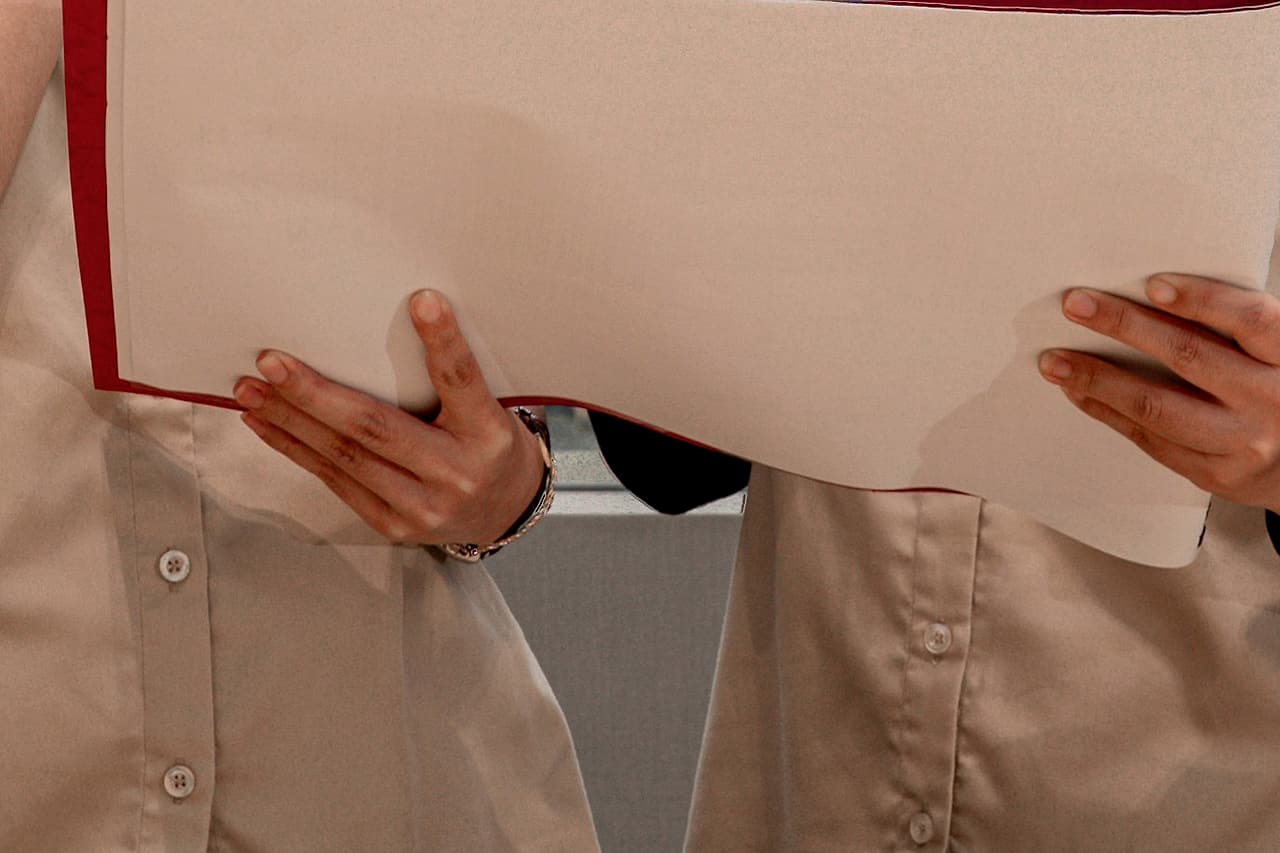 Two people hold a large sheet of paper during an indoor document review.