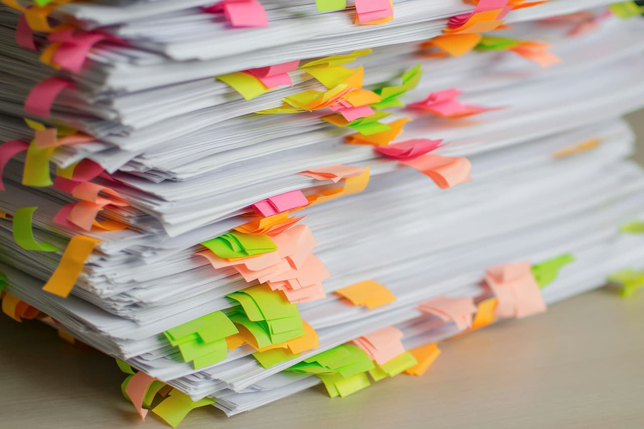 Stack of paper records separated with coloured index tabs.