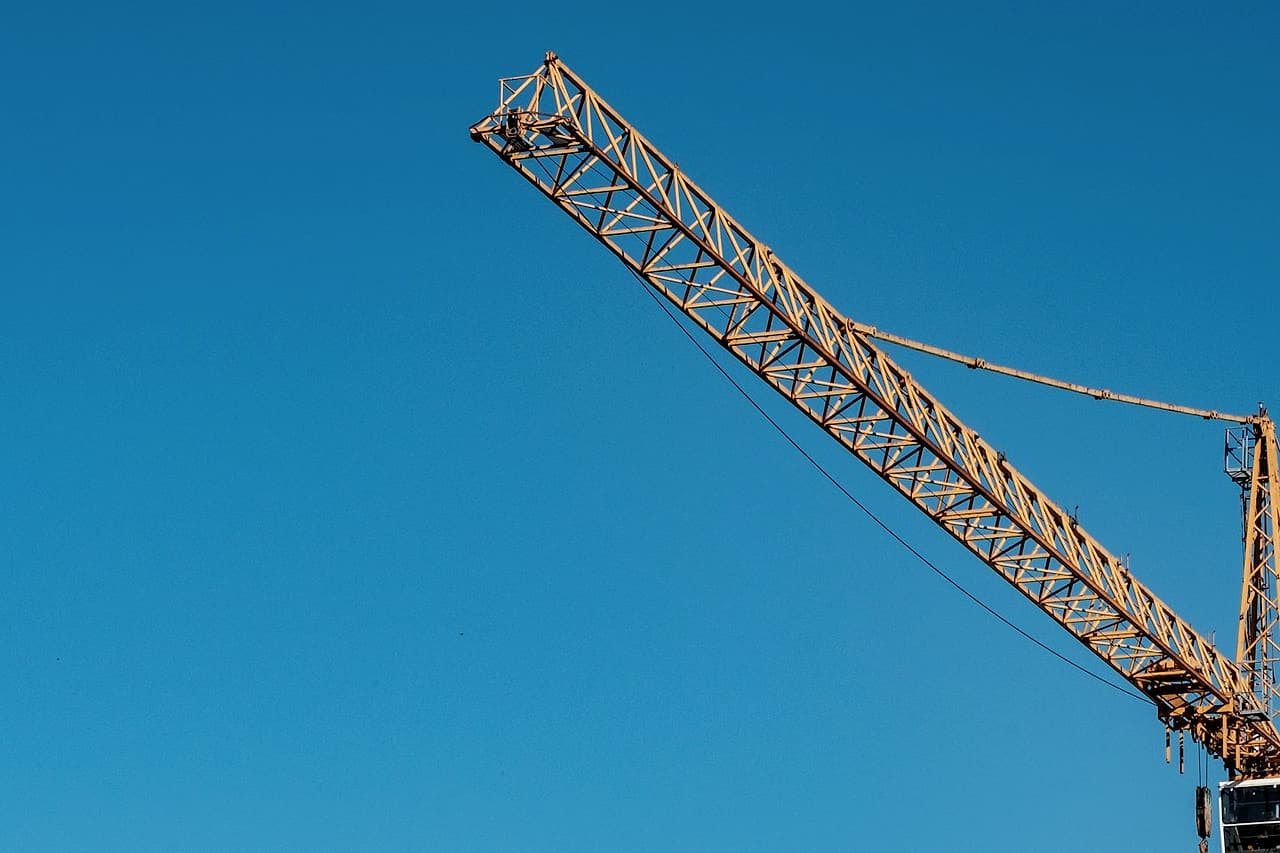 A tower crane jib extends across clear blue sky.