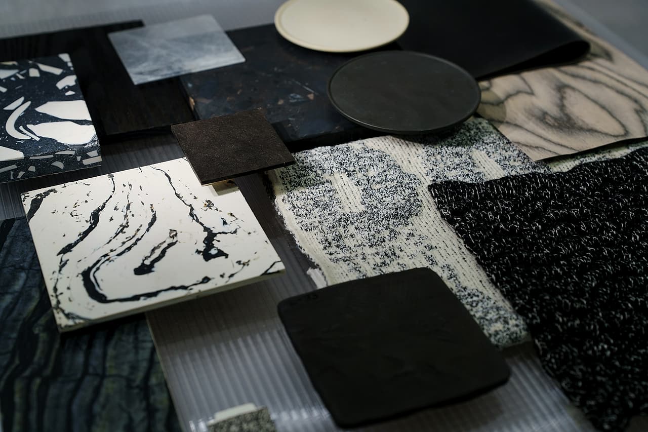 A selection of stone, fabric and other finish samples lies on a table.