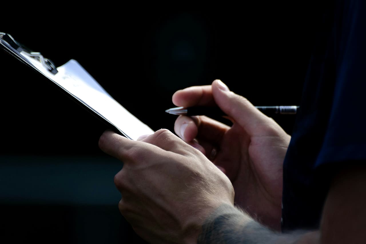 Close-up of a person's hands holding a clipboard and a pen, ready to write.