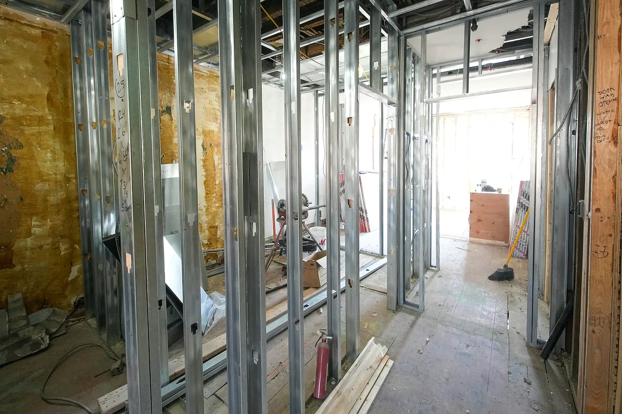 Half-finished metal stud partitions and overhead wiring in a building interior under renovation.