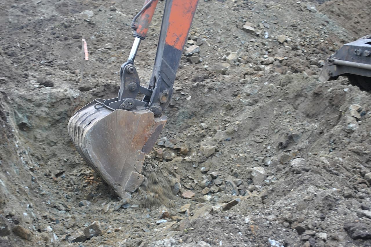 Excavator bucket working through rocky soil.