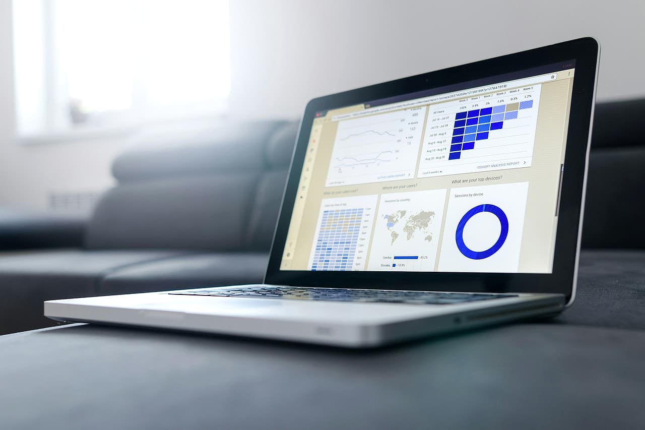 An open laptop displays several blue charts on a desk.