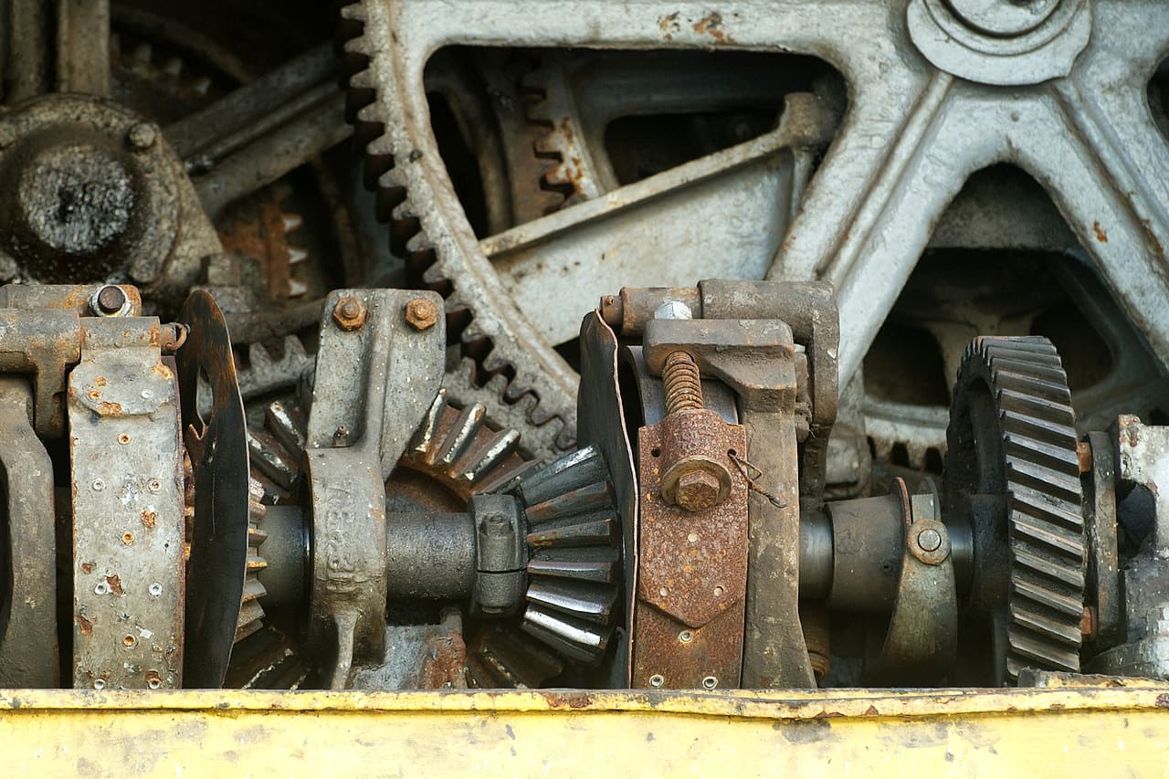 Worn metal gears and bearings inside an exposed machine mechanism.