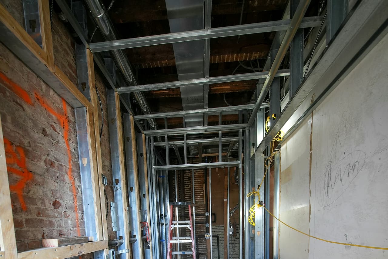 Exposed metal framing, ducts and wiring line an empty corridor under renovation.