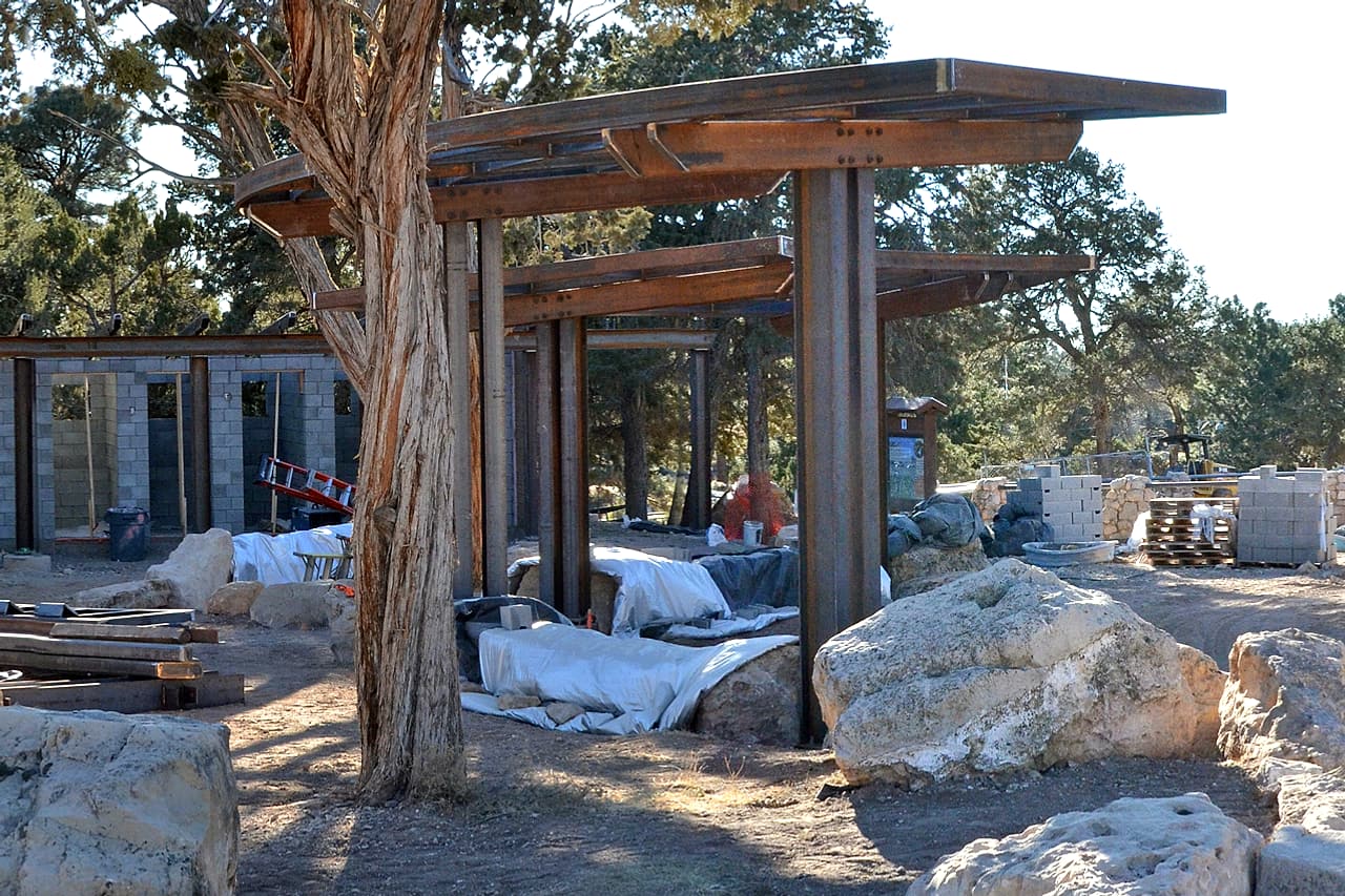 Steel canopy framing and stacked materials stand beside an unfinished block building.