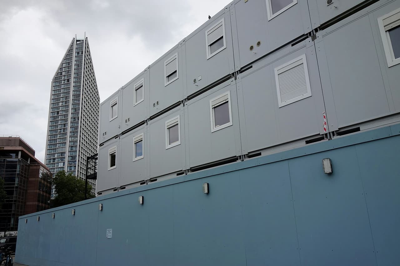 Rows of modular cabins sit behind a solid site perimeter wall.