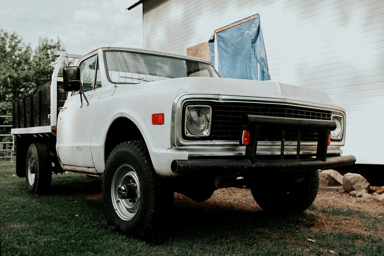 An empty flatbed truck is parked beside an unfinished building entrance.