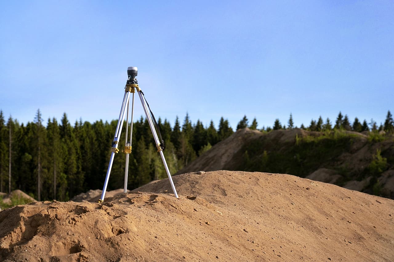 Surveying receiver on a tripod above exposed earth at a worksite.