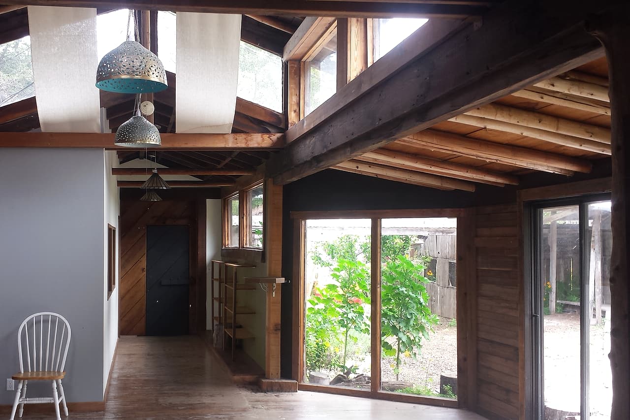 Daylight enters a finished timber interior with a chair and pendant lights.