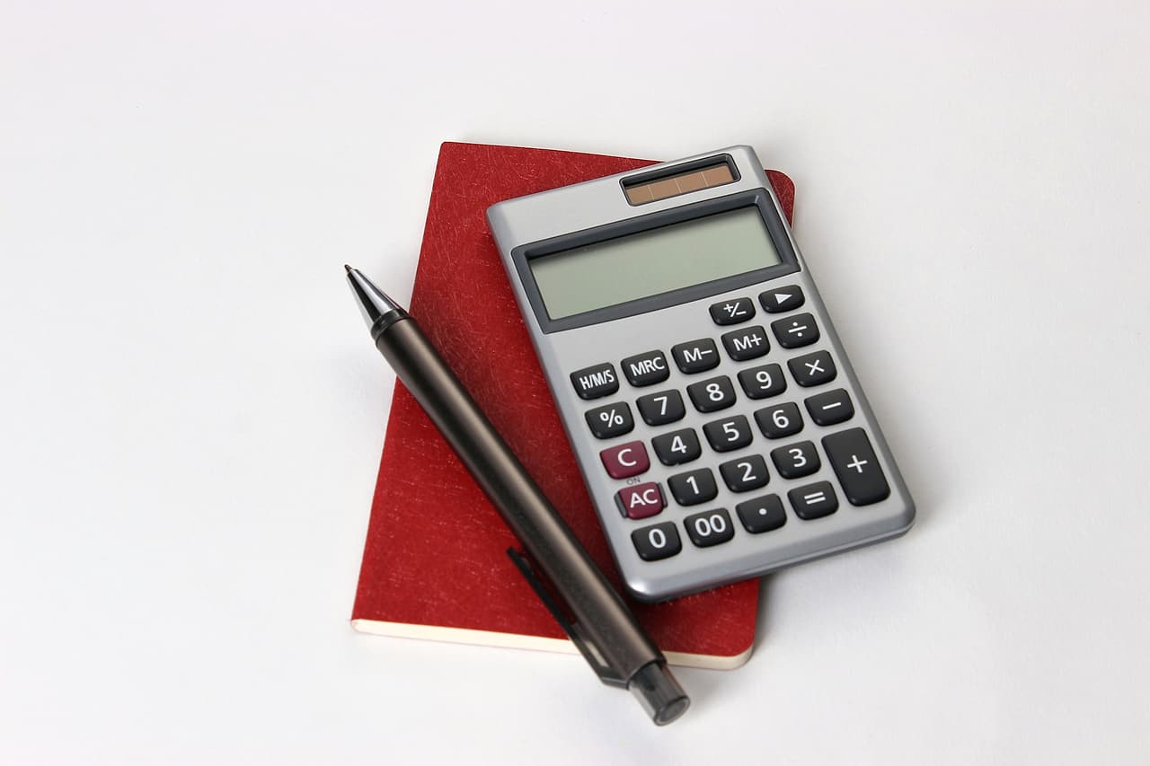 An unbranded calculator and pen rest on a red notebook.