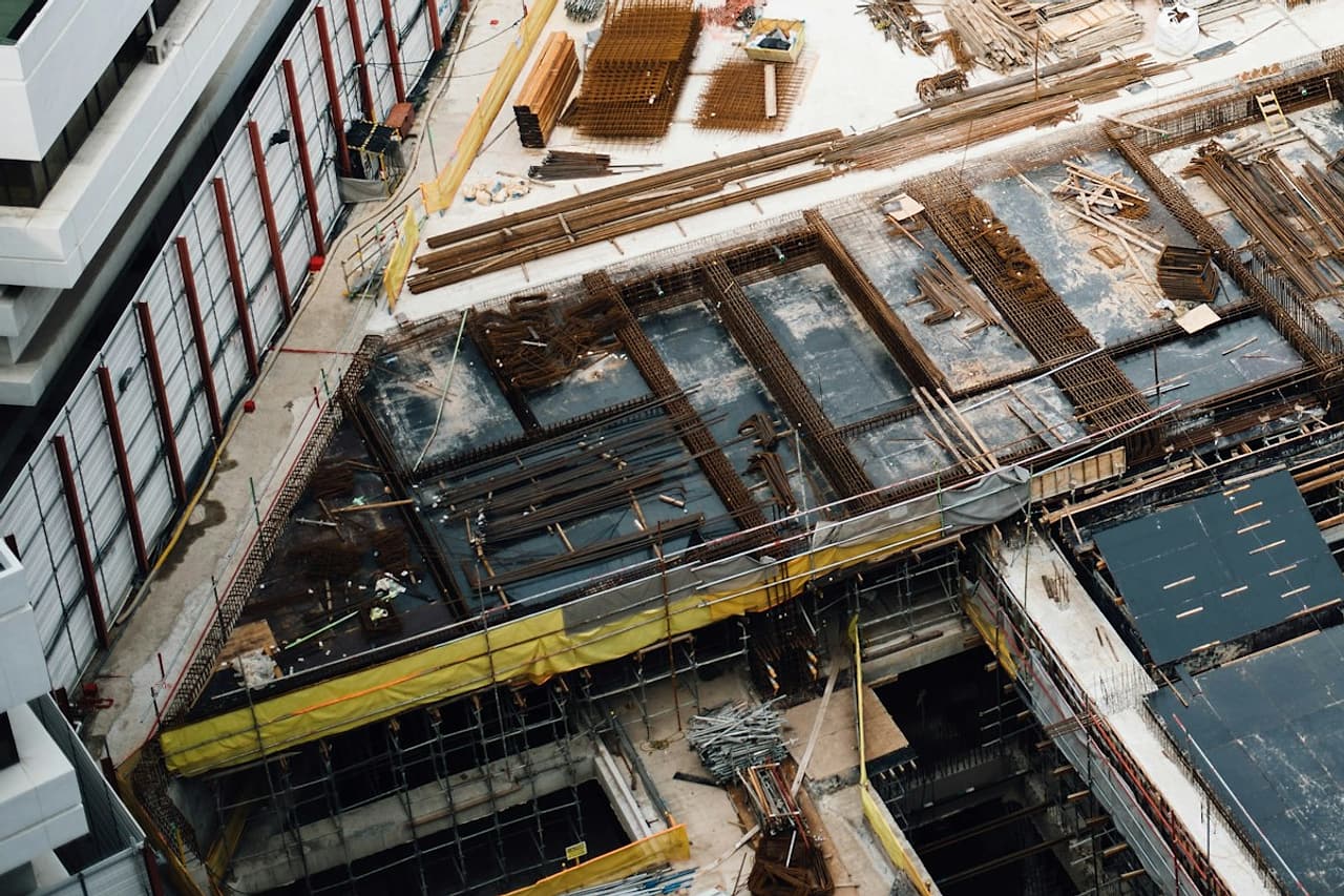 A construction site lies beside a completed building, viewed from above.