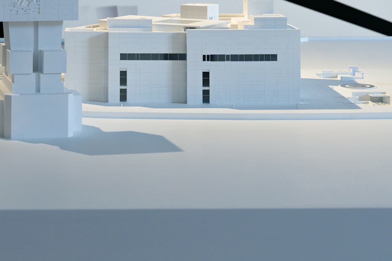 A white architectural model stands in front of plans.