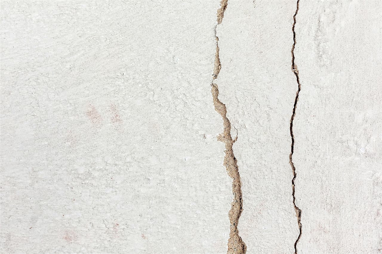Two cracks running down a white rendered wall.
