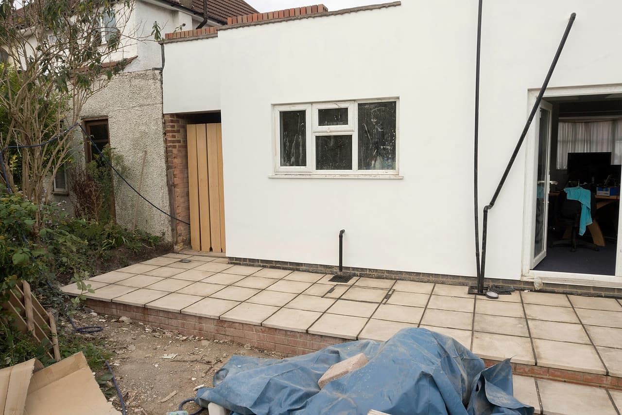 Materials are staged outside a small residential extension.