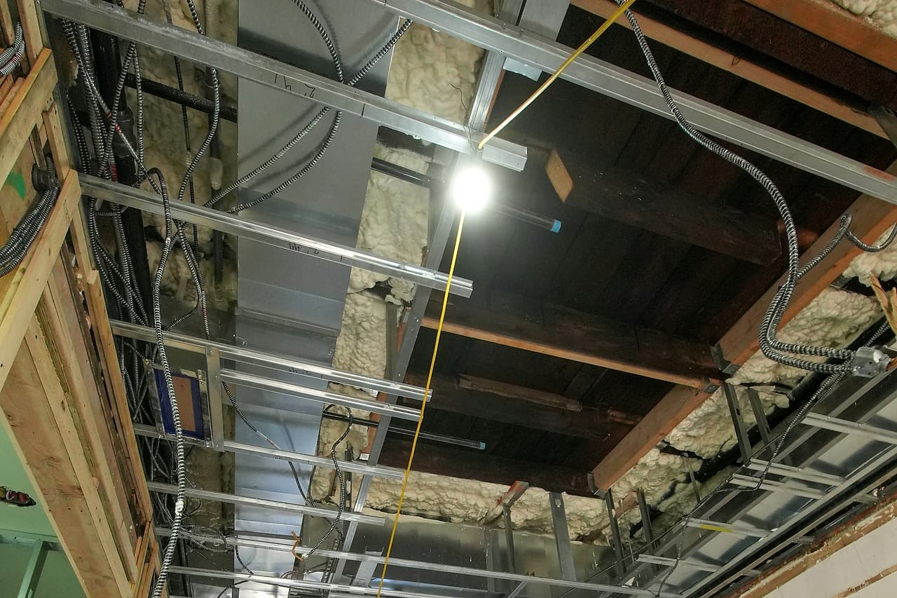 Exposed ceiling services and metal framing in an interior under renovation.