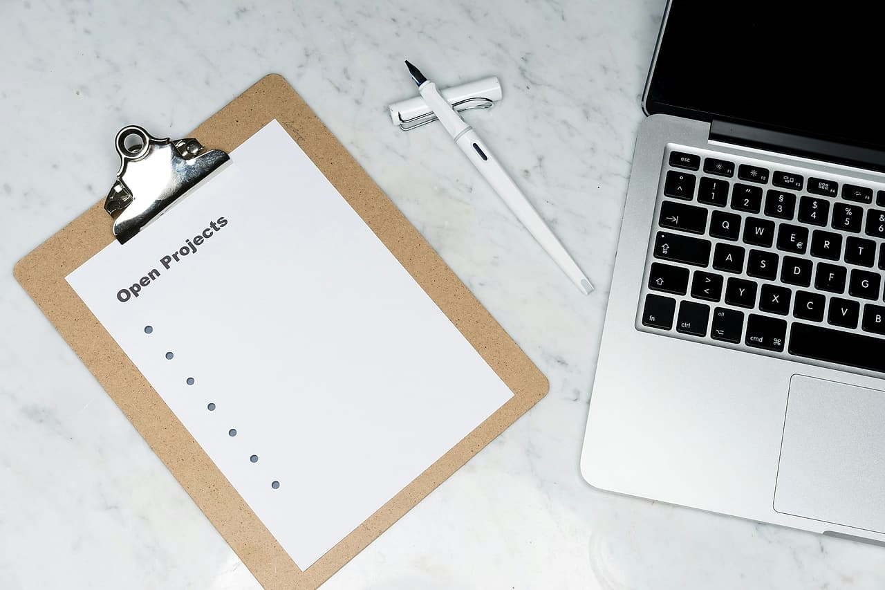 A clipboard headed Open Projects lies beside a laptop and pen.
