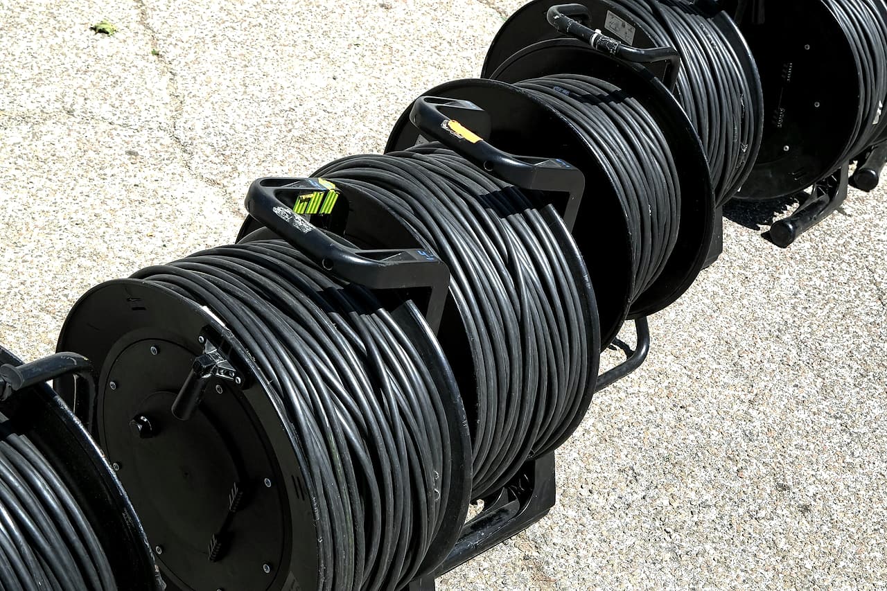 Several portable reels of black electrical cable are staged together on a concrete surface.