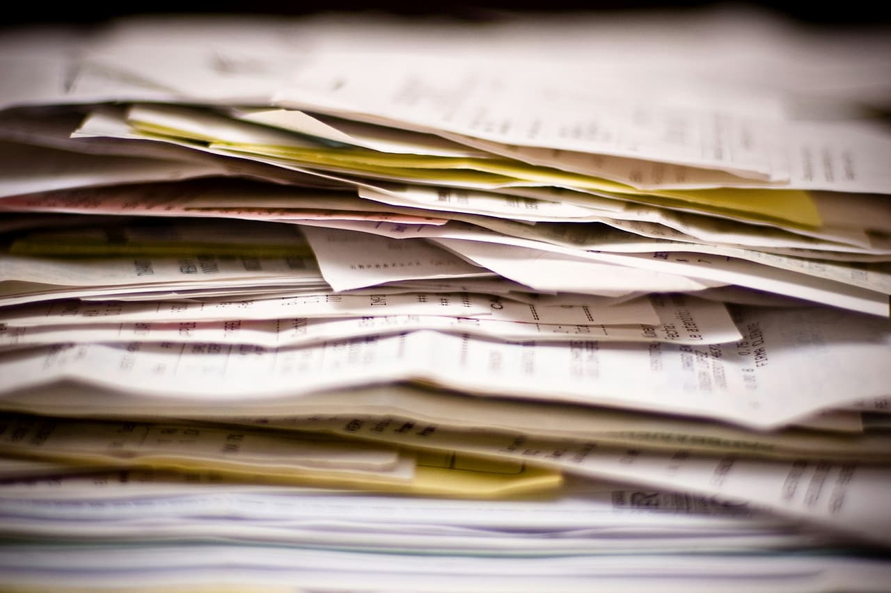 A thick stack of receipts and papers piled on a desk.