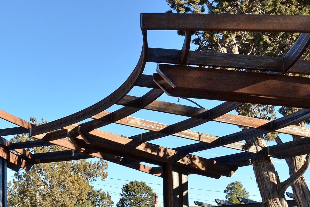Unfinished shade-shelter framing stands beneath a clear sky.