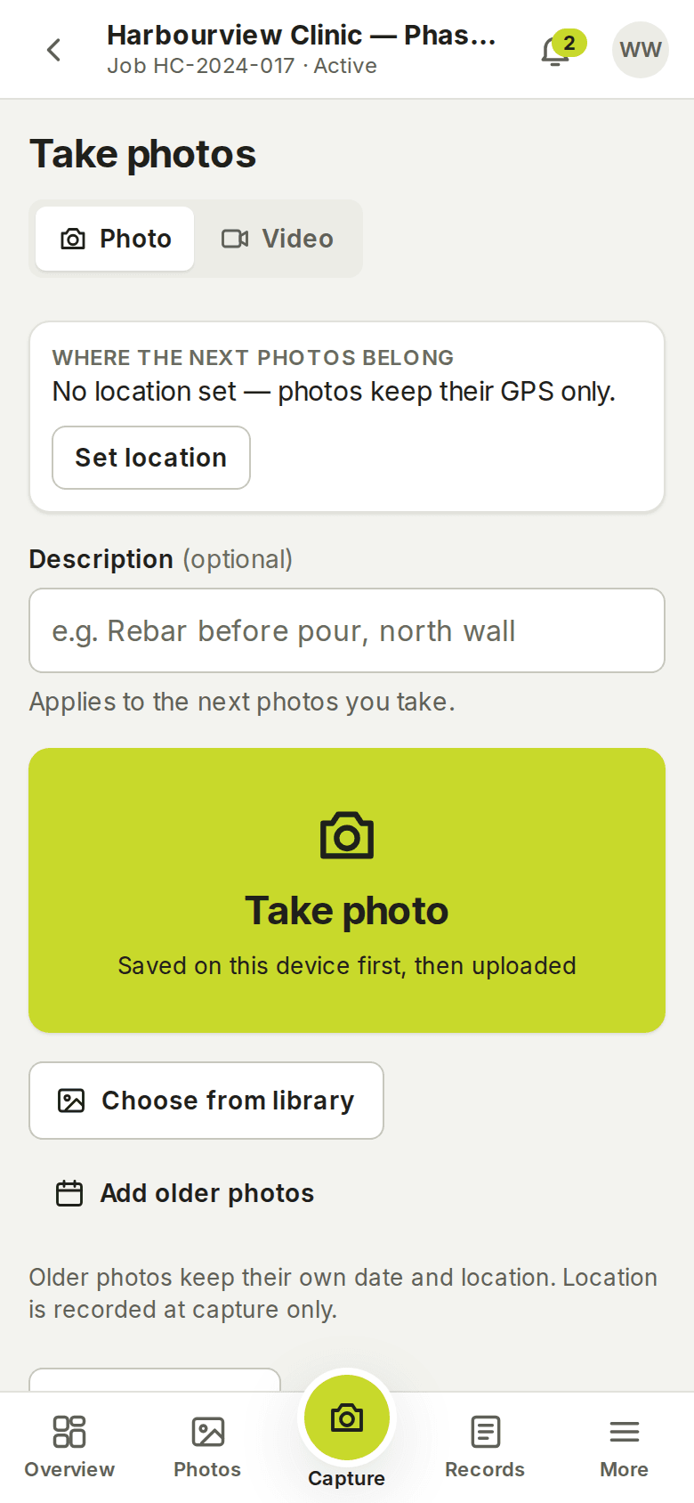 The capture screen on a phone: Photo and Video tabs, where the next photos belong, a description field, and a large Take photo button that says Saved on this device first, then uploaded.